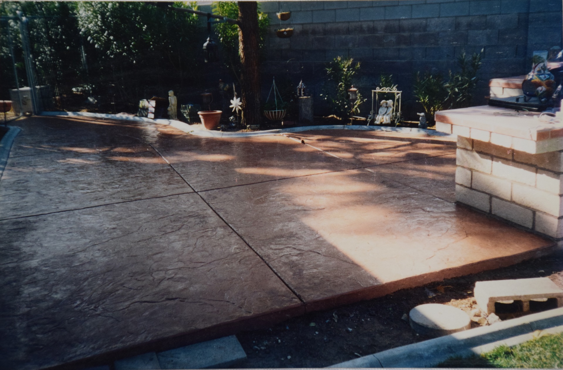 Rich dark stamped concrete patio with BBQ area and garden border