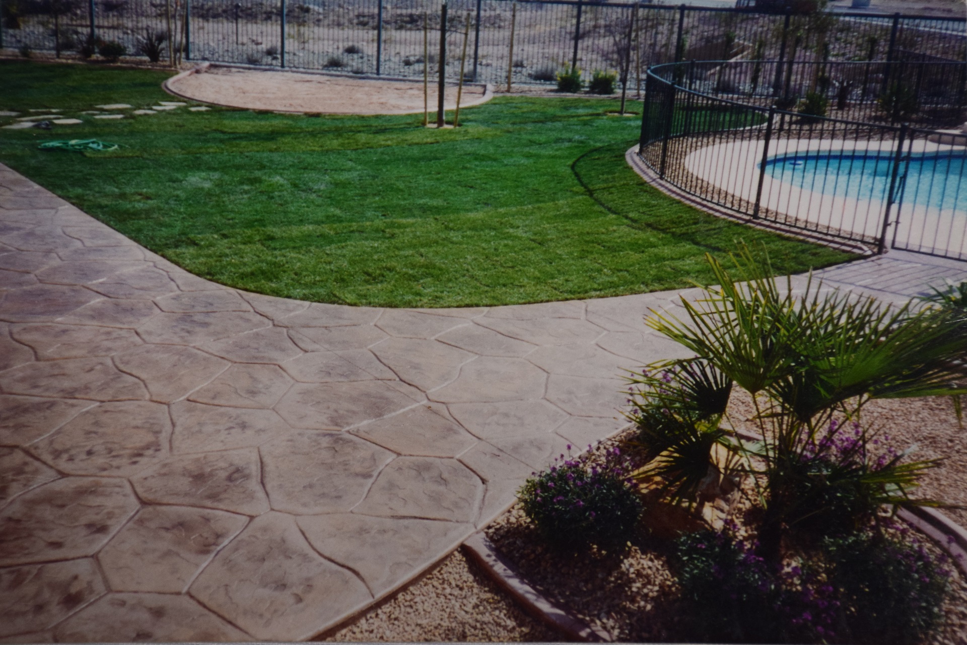 Curved dark charcoal concrete walkway connecting pool area