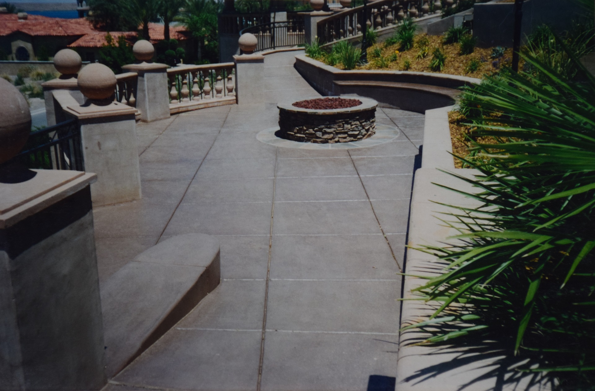 Decorative stamped stone-pattern concrete walkway through landscaped garden